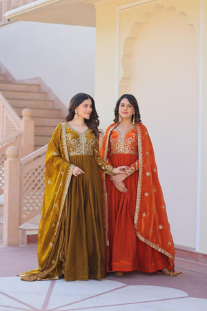Two women in traditional sarees standing in a decorative interior setting.