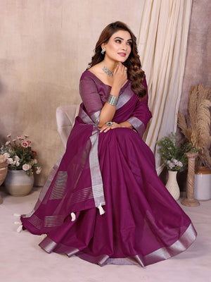 Woman in a purple saree with silver border posing indoors.