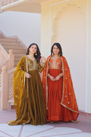 Two women in traditional embroidered dresses standing in a decorative interior setting.