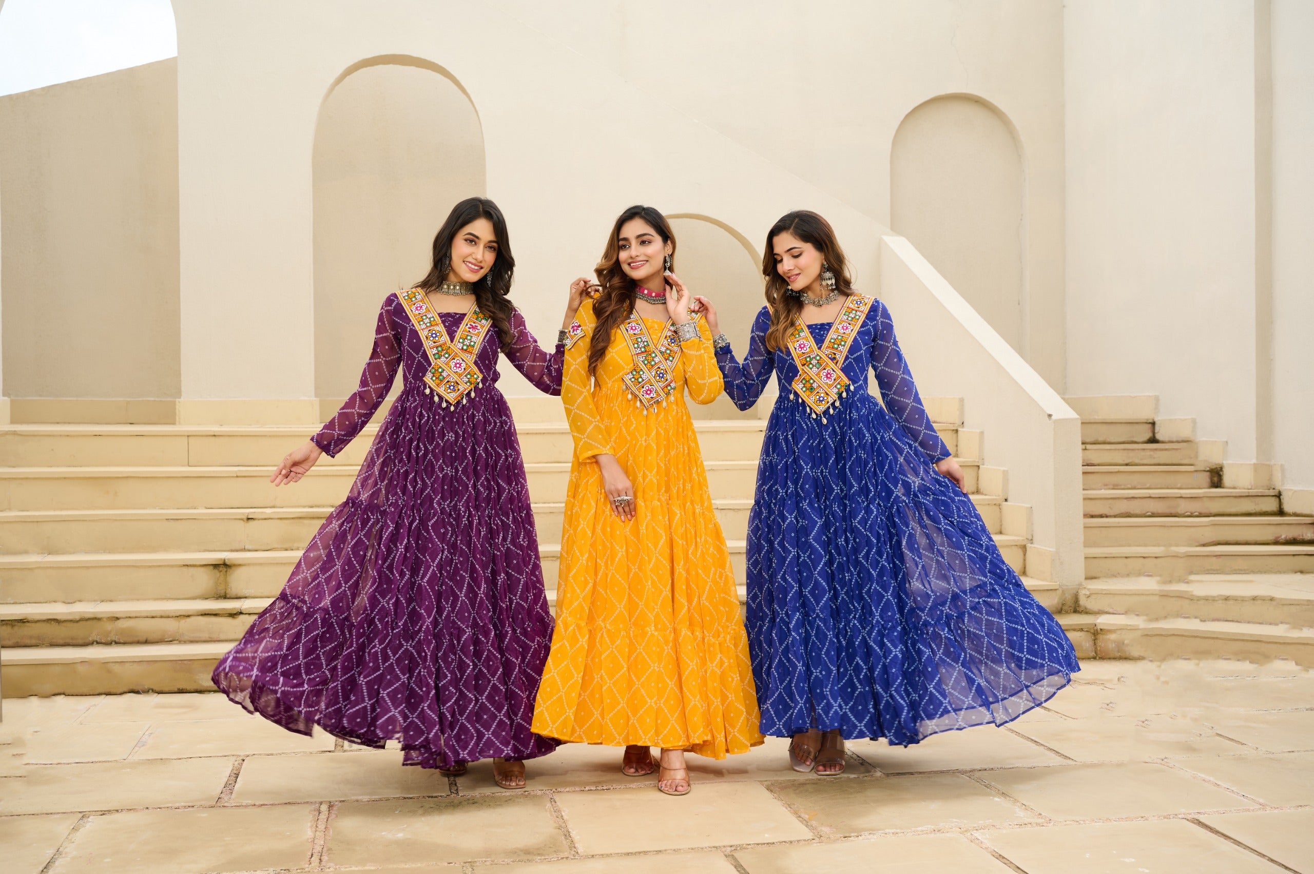 Three women in colorful traditional dresses standing on a stone staircase.