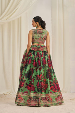 Woman wearing a green and red floral dress against a white curtain background