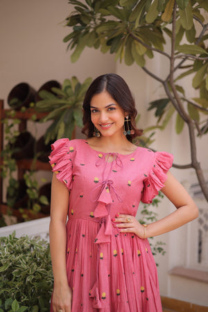 Woman in a pink dress standing outdoors with greenery in the background