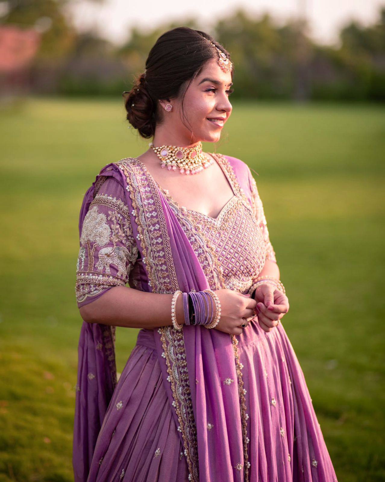 Bridal purple lehenga with dupatta twirling in garden