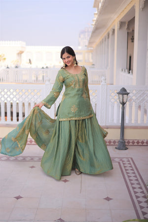 Woman in a green traditional outfit standing in front of a white building with columns.