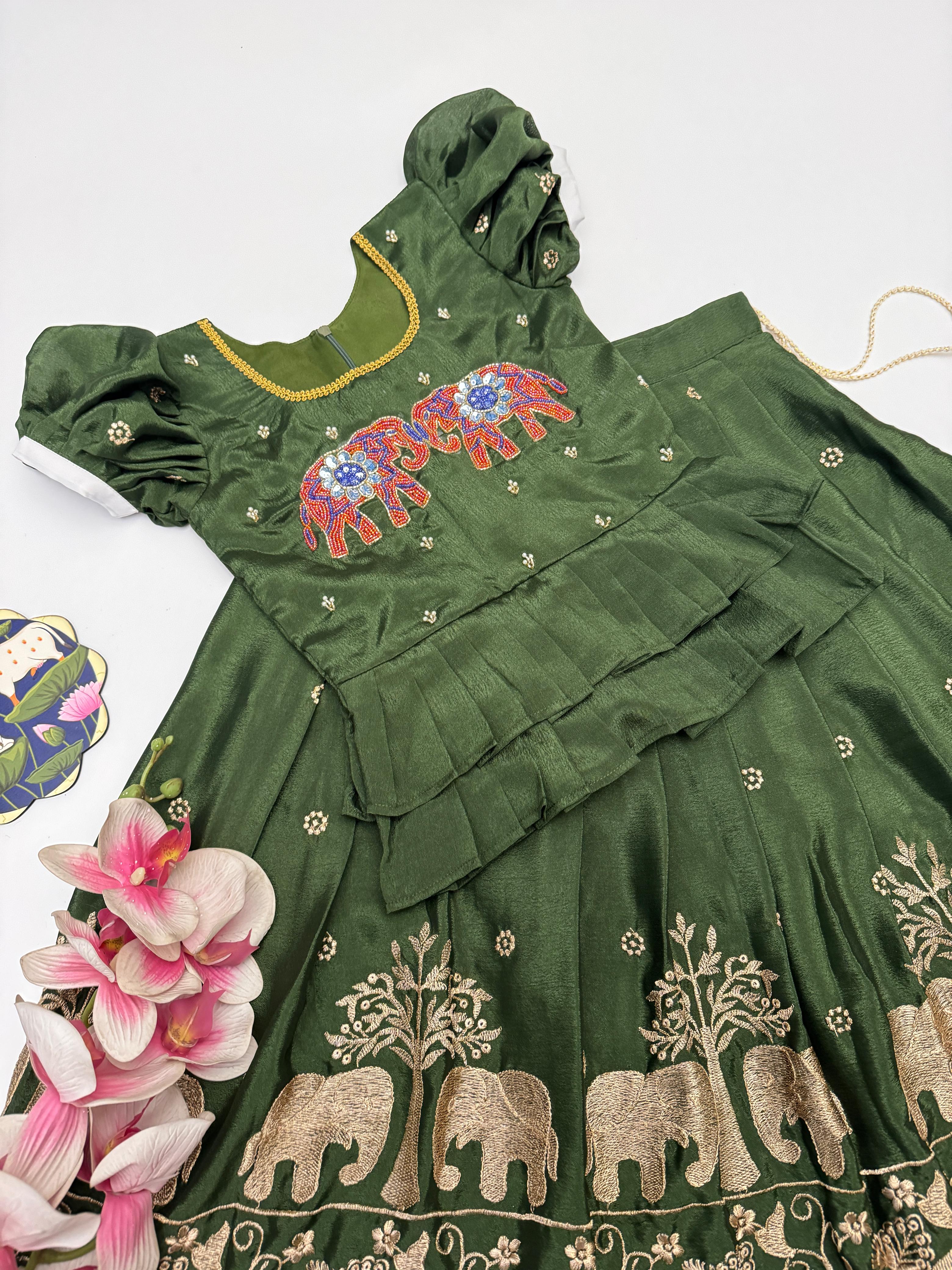 Green traditional outfit with elephant embroidery on a white background
