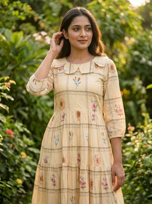 Woman wearing a beige dress with floral patterns in a garden setting