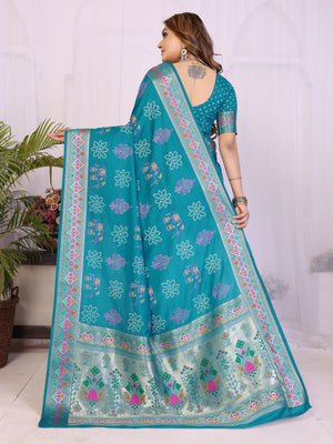 Woman wearing a teal saree with floral patterns in a home setting