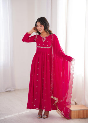 Woman wearing a pink embroidered dress with a white background