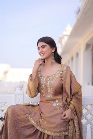 Woman in traditional outfit with gold and brown colors, standing outdoors.