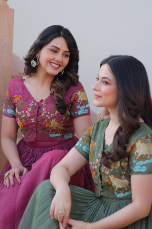 Two women in traditional outfits sitting and smiling against a neutral background