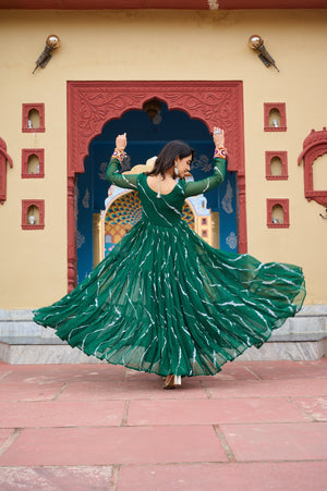 Woman in a green dress twirling in front of a decorative archway.