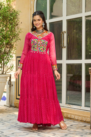 Woman wearing a vibrant pink traditional outfit with colorful embroidery in an outdoor setting.
