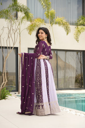 Woman in a purple traditional outfit standing by a pool with a building and trees in the background