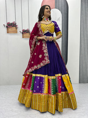 Woman wearing a colorful traditional outfit with a purple and yellow dress against a white background.