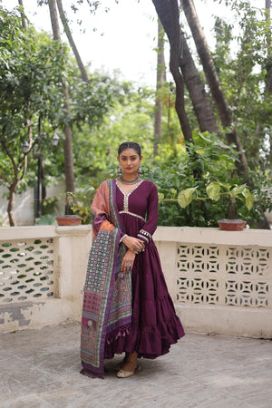 Woman in a wine color traditional outfit standing on a balcony with greenery in the background