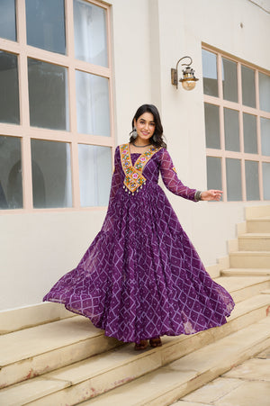 Woman in a purple dress with intricate designs standing on steps outdoors.