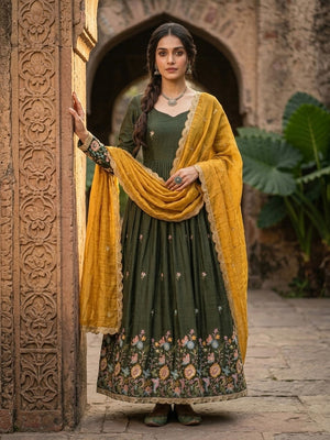Woman in a green traditional outfit with a yellow dupatta standing in front of an archway.
