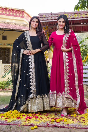 Two women in traditional outfits standing on a decorated ground with flowers.