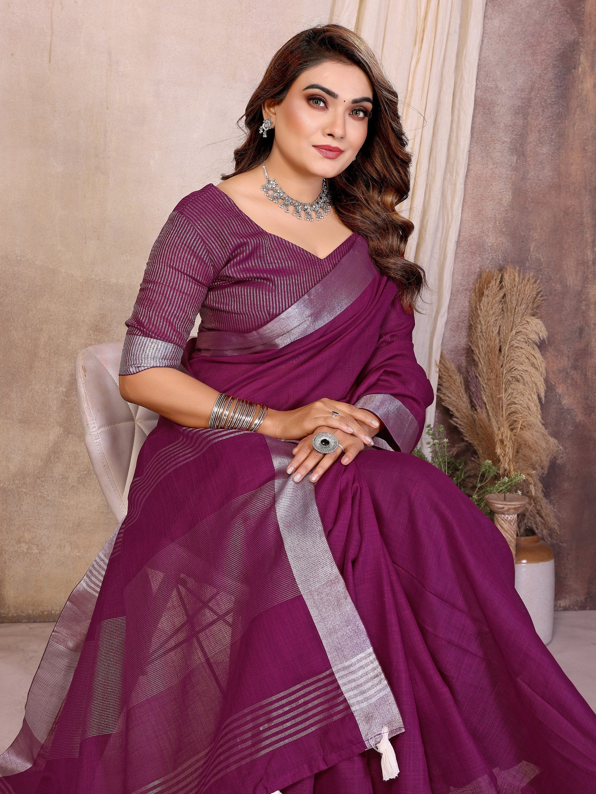 Woman wearing a purple saree with silver border indoors