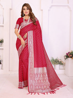 Woman wearing a red saree with white patterns in a white room.