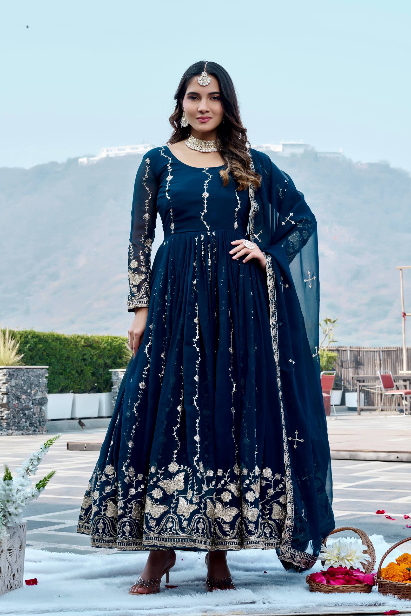 Woman in a dark blue traditional outfit with white patterns standing outdoors.