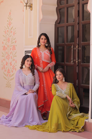 Three women in colorful traditional dresses posing indoors.