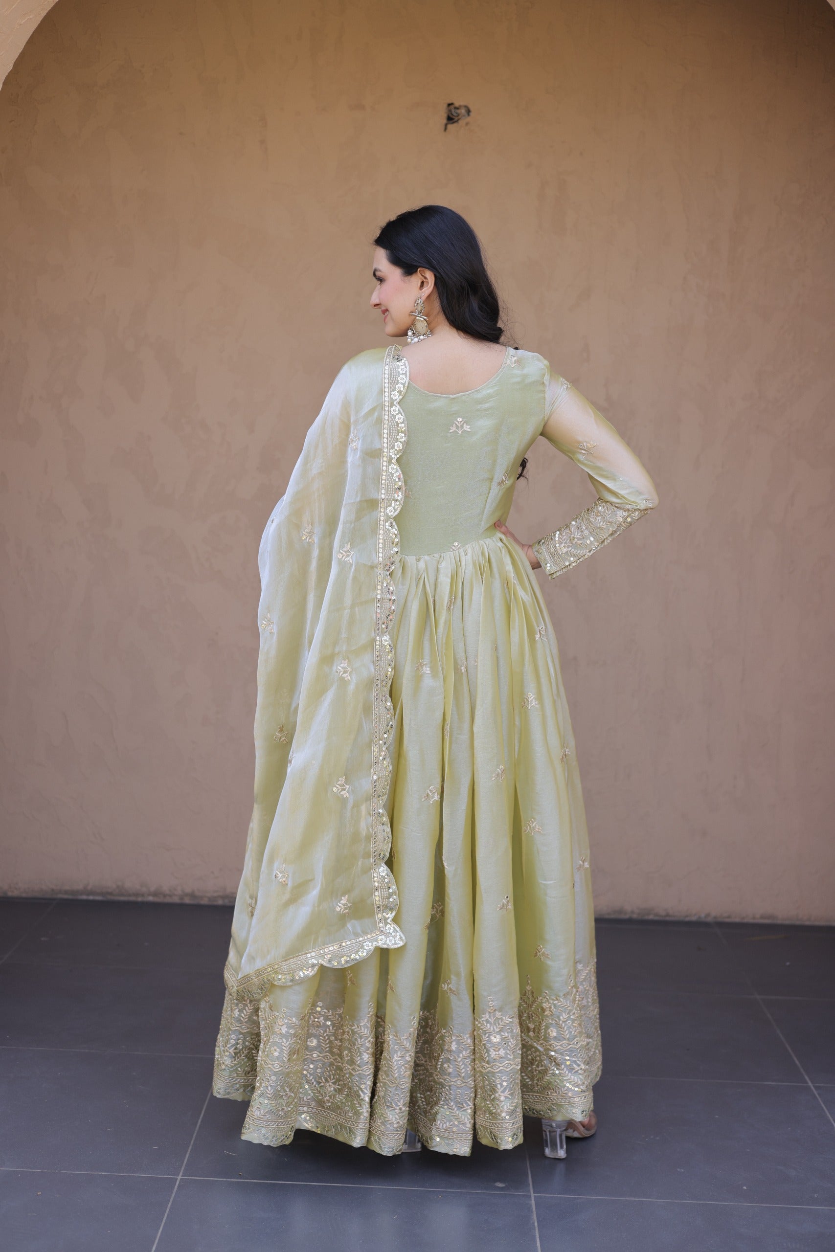 Woman wearing a light green traditional outfit with a beige background