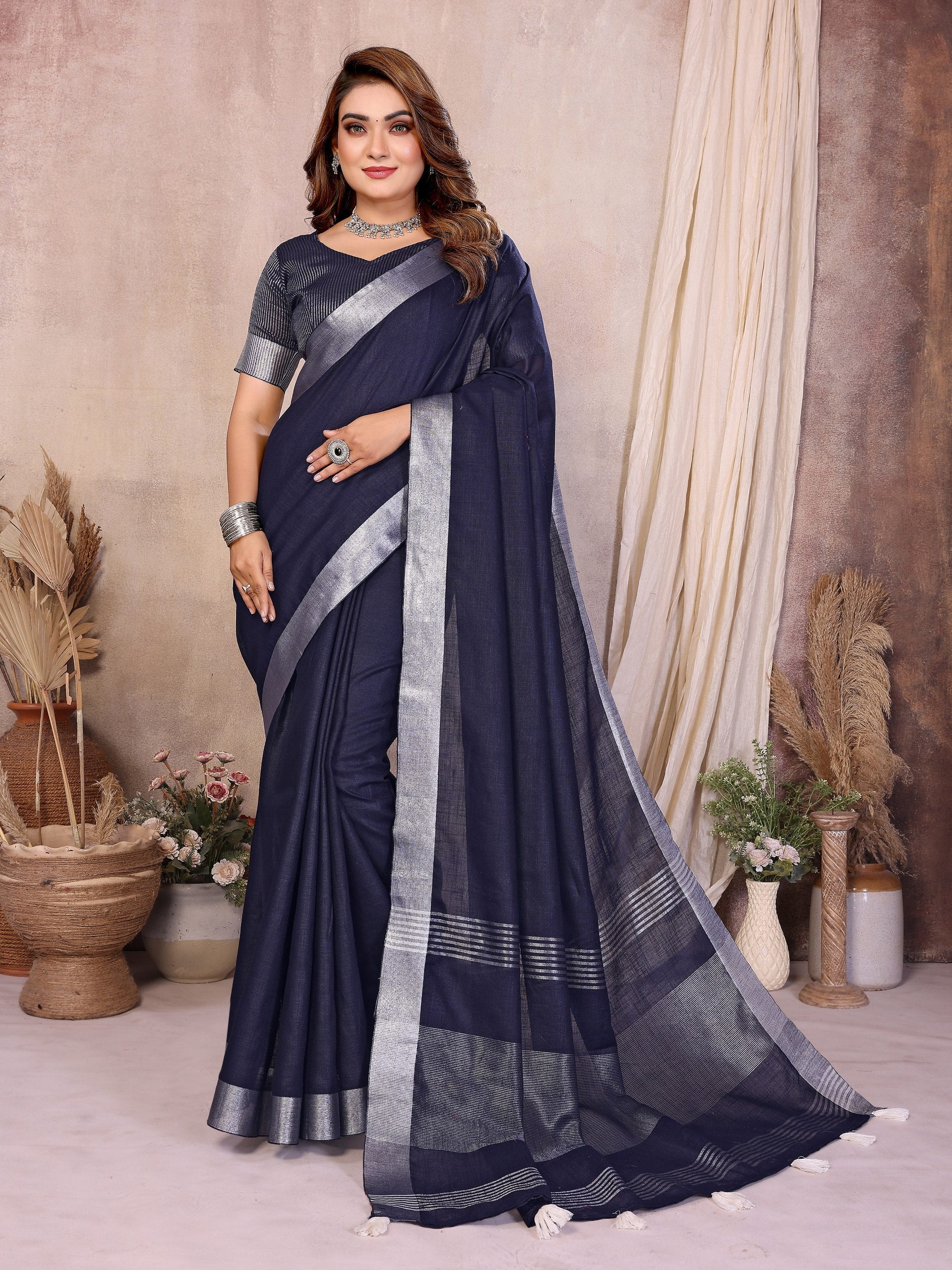 Woman wearing a navy blue saree with silver border in an indoor setting.