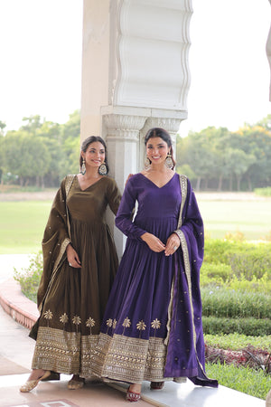 Two women in traditional outfits standing outdoors with greenery in the background
