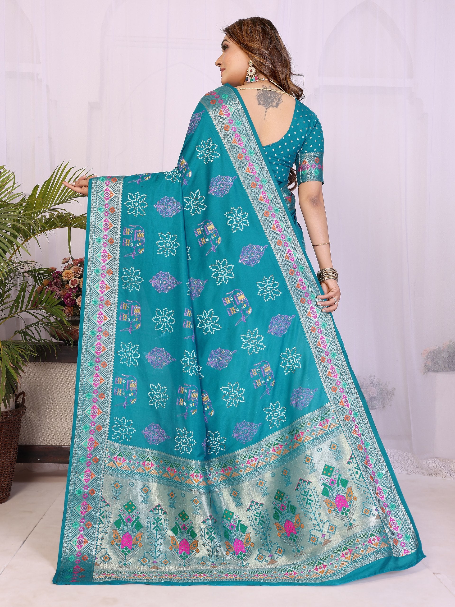 Woman wearing a teal saree with floral patterns in a home setting