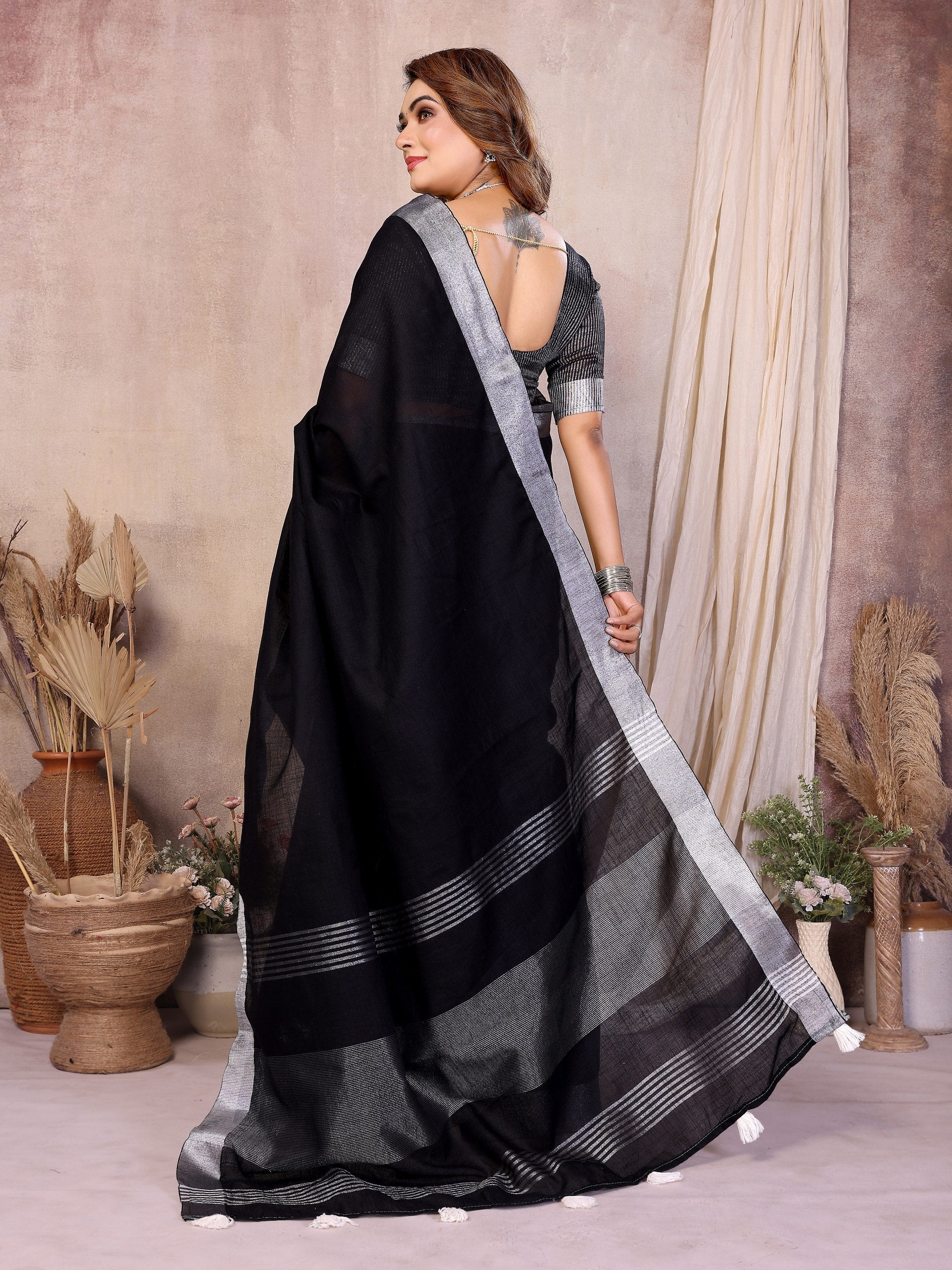 Woman wearing a black saree with silver border in an indoor setting
