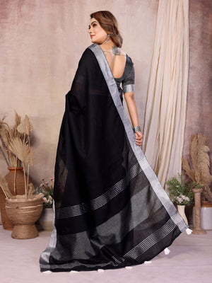Woman wearing a black saree with silver border in an indoor setting
