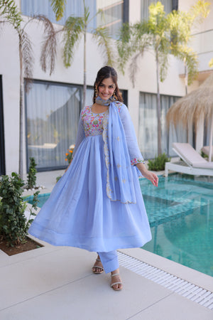Woman in a light blue traditional outfit standing by a poolside.