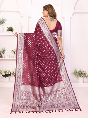 Woman wearing a maroon saree with white patterns in a bright room.