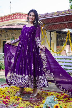 Woman in a purple traditional outfit standing on a decorated ground with flowers.