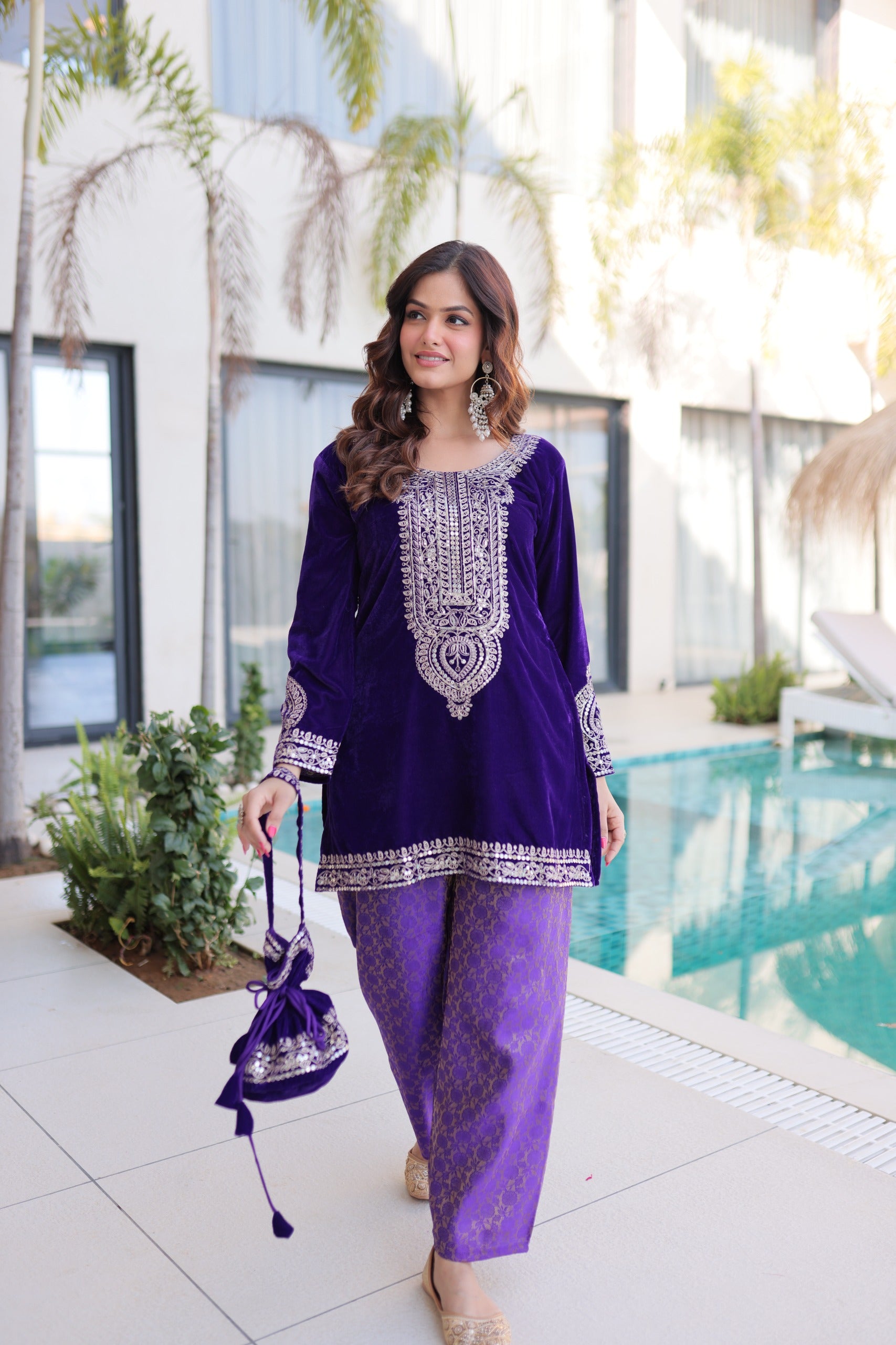 Woman in a purple traditional outfit standing by a poolside.