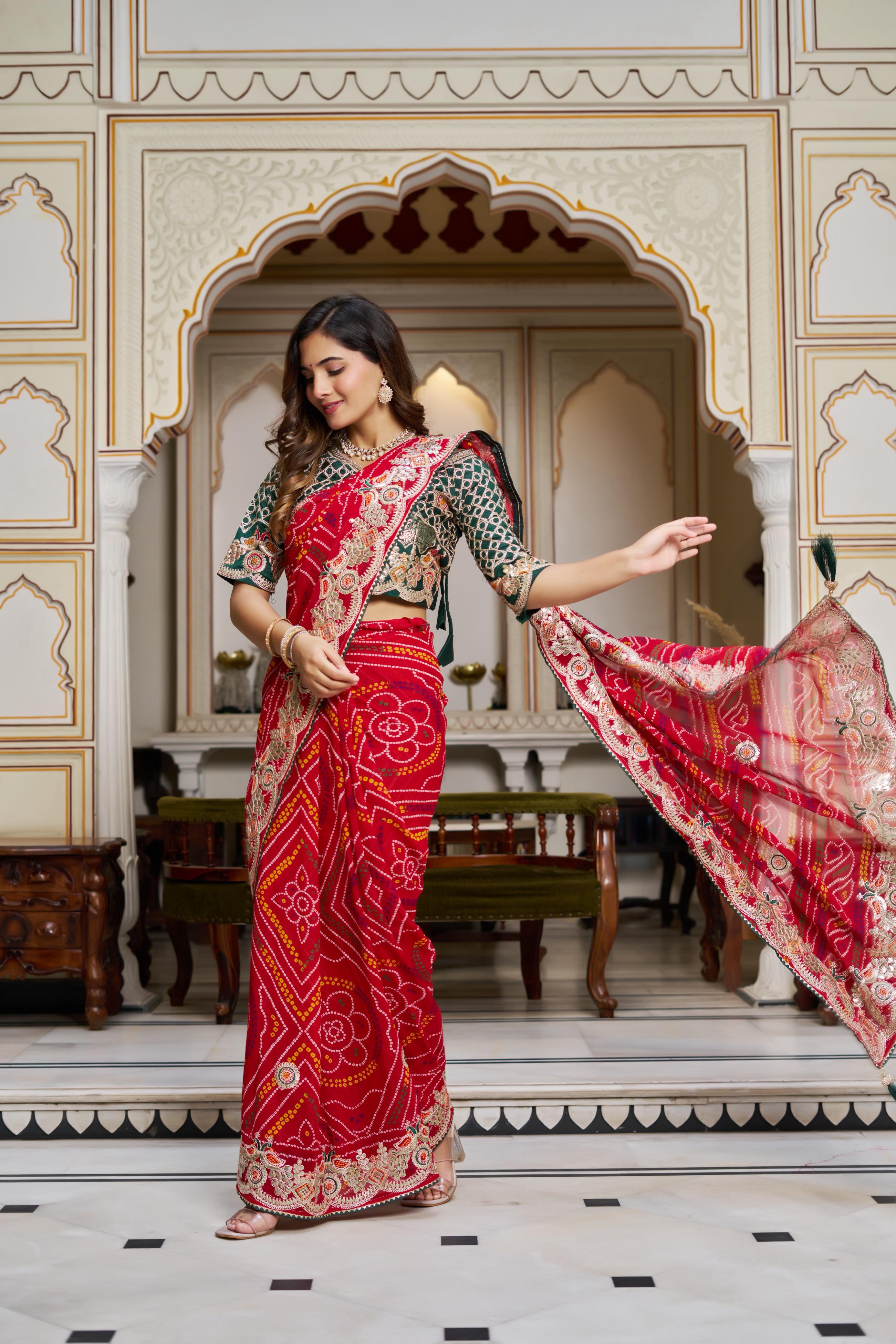 Woman posing in designer red Bandhej saree with heavy gota patti embroidery vastralyn