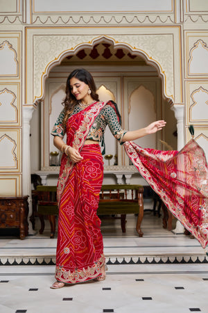 Woman posing in designer red Bandhej saree with heavy gota patti embroidery vastralyn