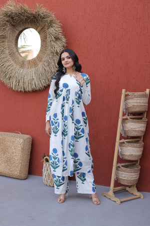 Woman in a floral dress standing against a red wall with woven baskets.