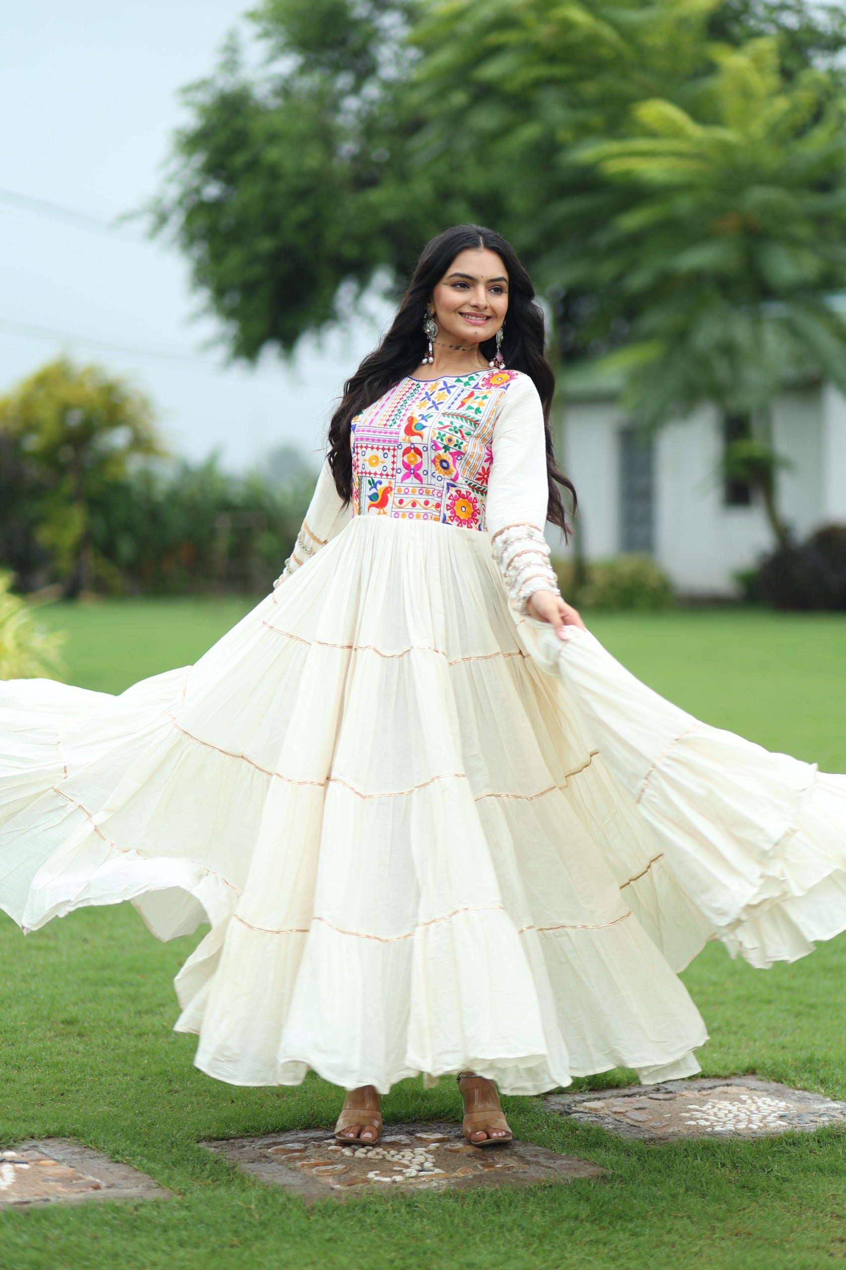 Woman in a white traditional outfit with colorful embroidery standing on grass