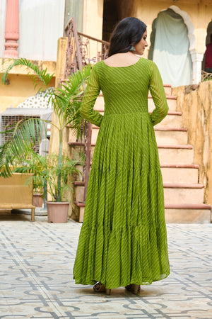 Woman in a green dress standing in an outdoor setting with plants and steps.