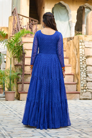 Person wearing a blue dress with long sleeves in an outdoor setting.