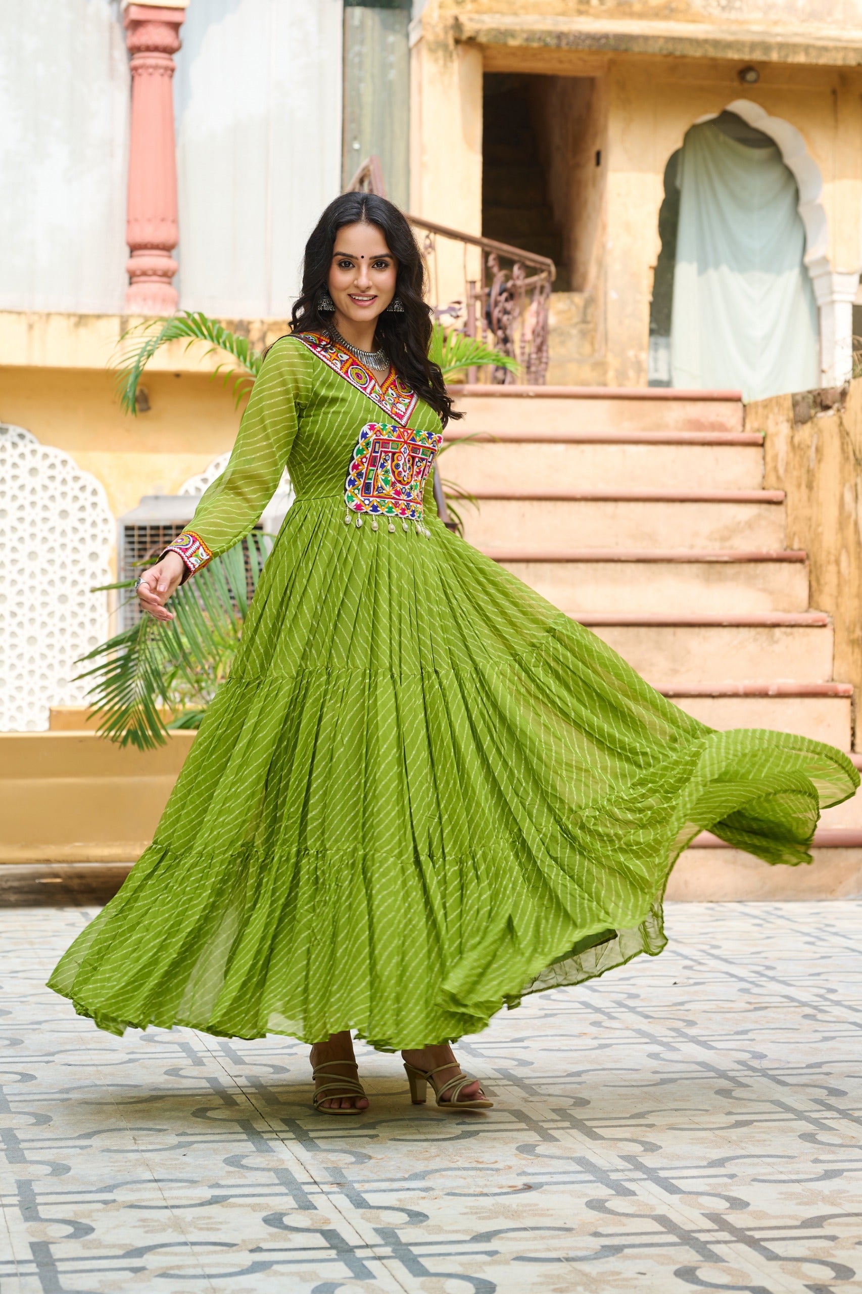 Woman in a green traditional outfit standing in front of a building.