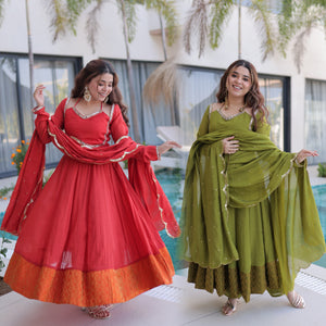 Two women in red and green traditional outfits standing outdoors.