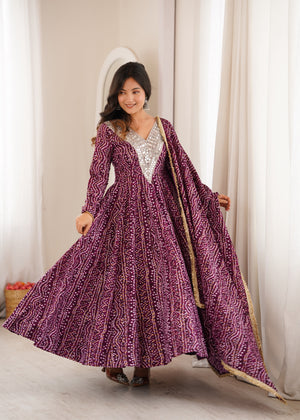 Woman wearing a long purple patterned dress with a matching shawl indoors.