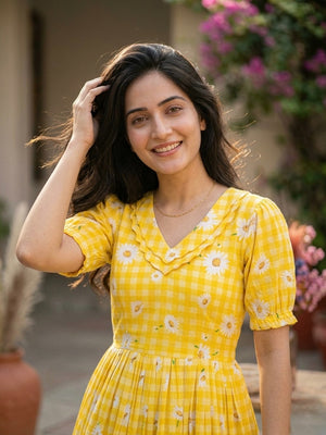 Woman in a yellow floral dress standing outdoors with plants in the background